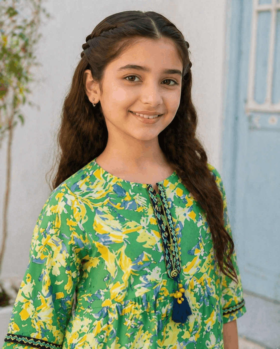 Young girl wearing a green and yellow floral dress with a white background