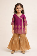 Young girl wearing a purple and gold traditional outfit on a beige background